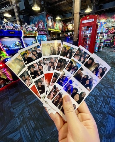 Jane Zeng holding photos of herself with friends at an arcade