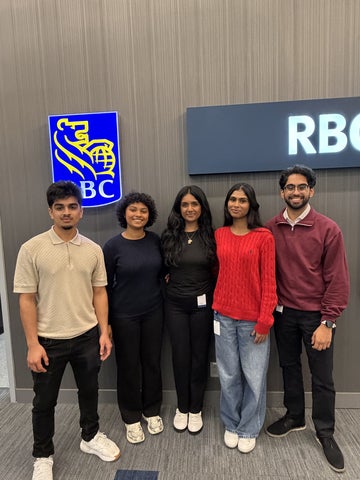 Rasana Yogarajan posing with four colleagues in front of RBC signage at the office.