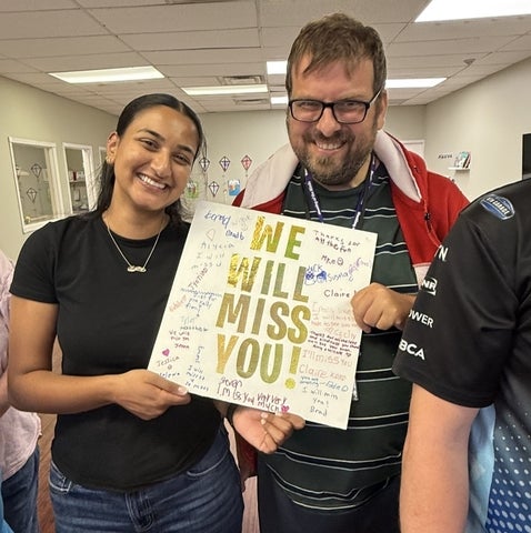 Kelly Ramnarais posing with a patient holding a sign that says "We will miss you!"