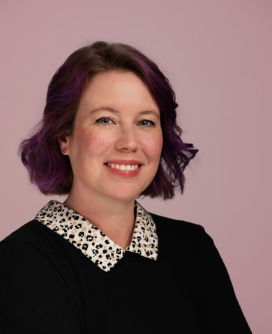 Laura Ashfield headshot, smiling wearing a black shirt with leopard print collar