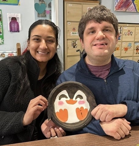 Kelly Ramnarais posing with a man holding a craft made on a paper plate