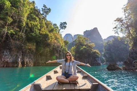 Woman relishing a serene boat journey through the lush karst landscape of Thailand's Khlong Sok
