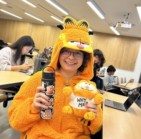 Phoenix Rogoz smiling in a Garfield costume holding a Garfield plushie and a water bottle