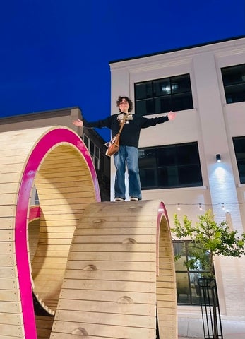 Phoenix Rogoz posing on top of a wooden statue