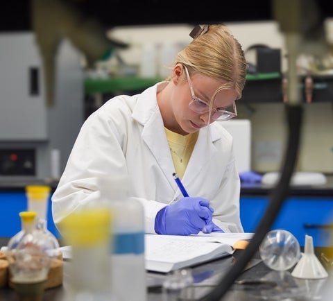 Allysa Greidanus writting notes in a science lab