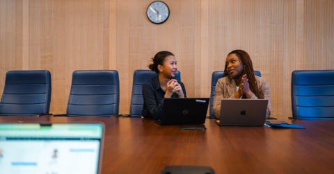 An employer and a student sitting at a table discussing something on a laptop