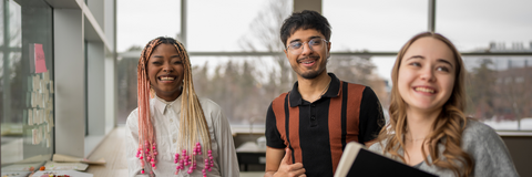 students laughing by a whiteboard looking off camera