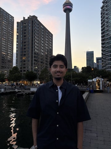 Vivek Upadhyay standing by the Toronto waterfront with the CN Tower in the back