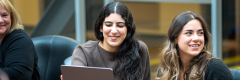 students sitting at a table with their laptops