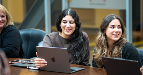 students sitting at a table with their laptops