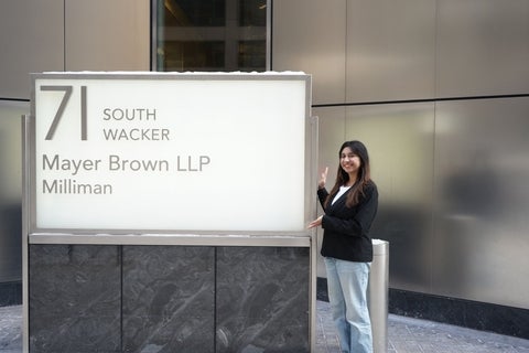 Avni standing beside a large sign for South Wacker Drive and May Brown LLP Milliman outside a modern office building.