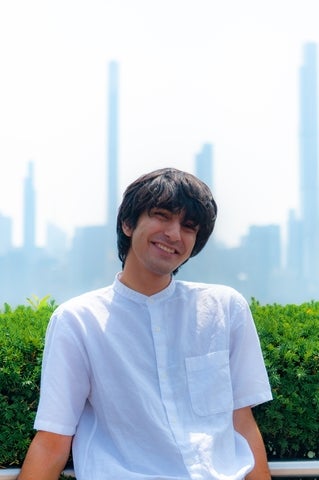 Zain Salman smiling with buildings in the distance behind him