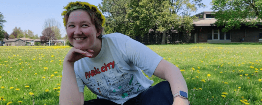 University of Waterloo Environment co-op student, Charlie Jou-ter Woort, sitting on grass and smiling.