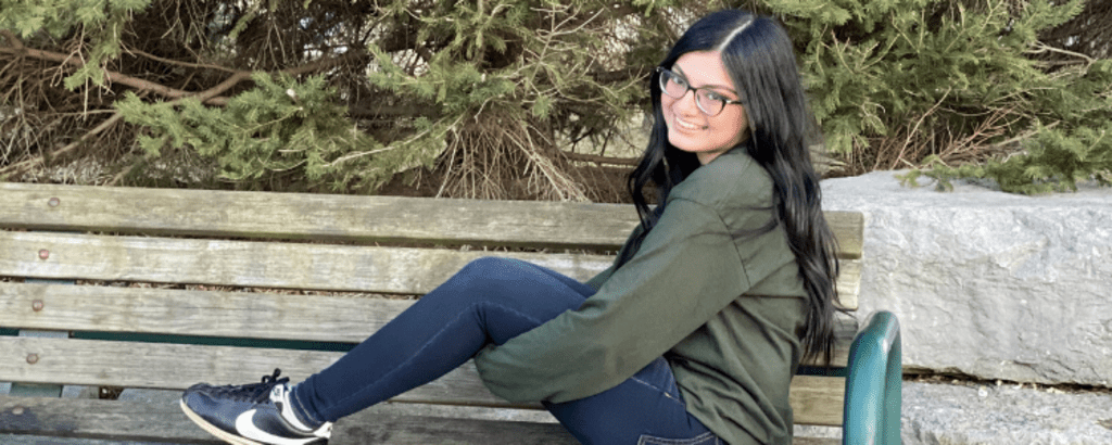 University of Waterloo Engineering co-op student, Sana Allana, sitting on a park bench and smiling.
