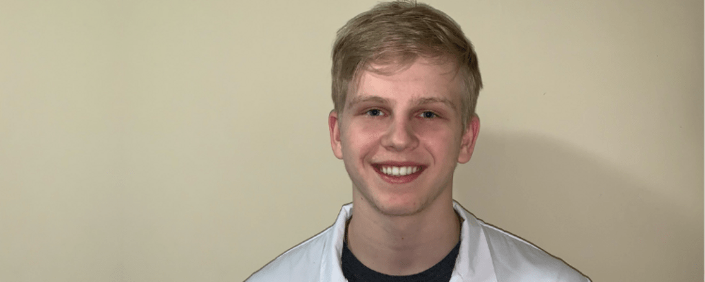 A photo of co-op student Max wearing a University of Waterloo lab coat.