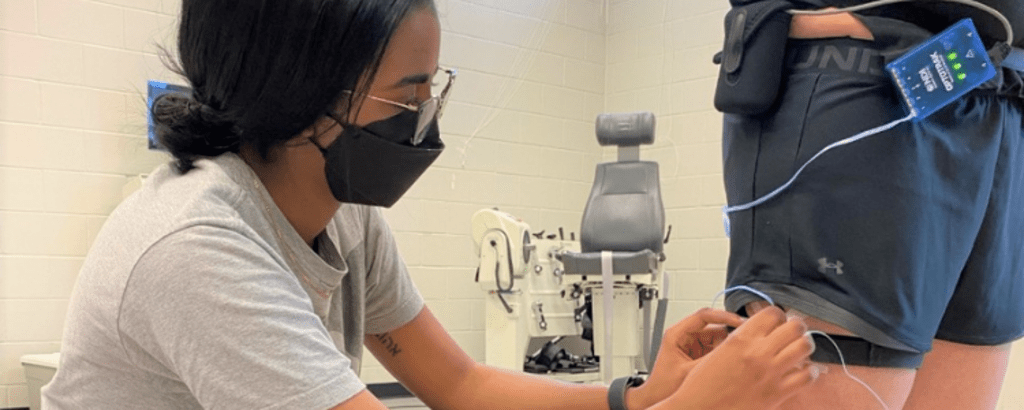 A photo of Waterloo health student Rachel hooking wires on a person on her co-op job experience. . 