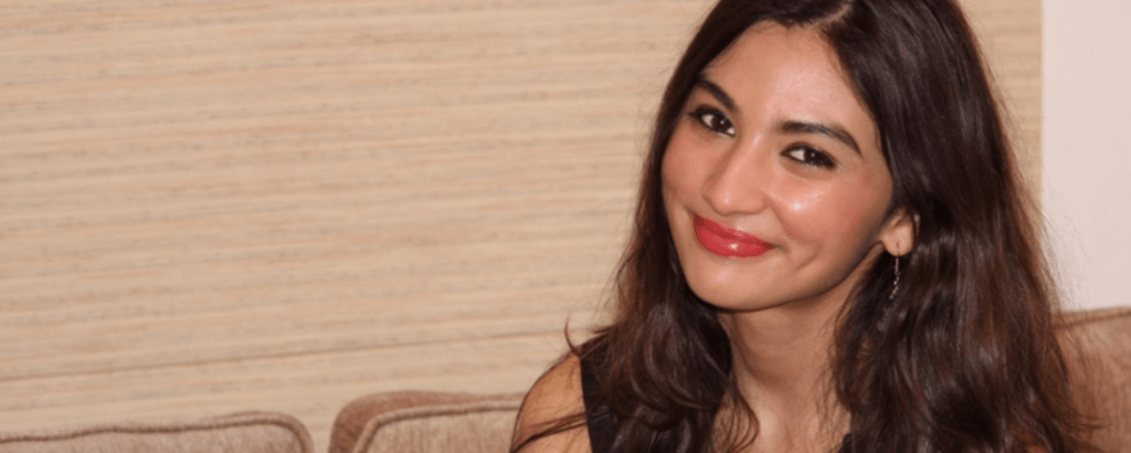 A photo of Manvi, a UWaterloo arts co-op student, sitting on a sofa and smiling.
