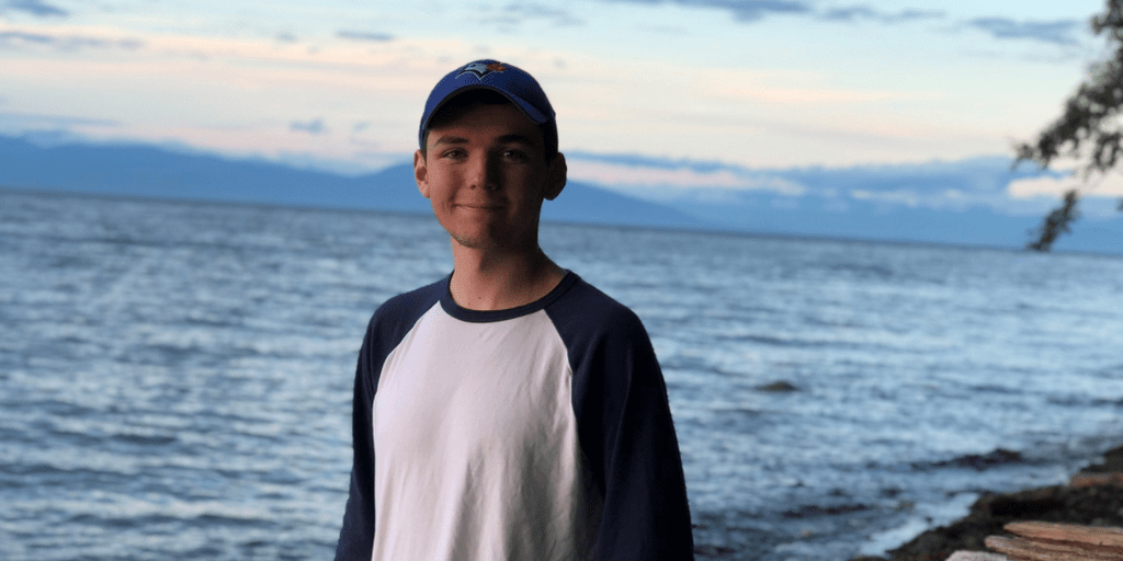 University of Waterloo student Jordan Ducatel, 3B Honours Physics and Astronomy student smiling by a lake.