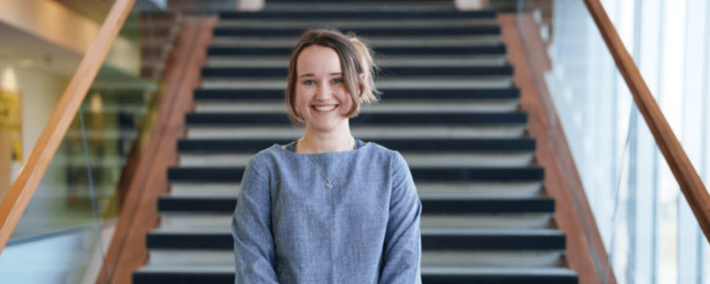 Frances Hallen smiling while standing in front of staircase