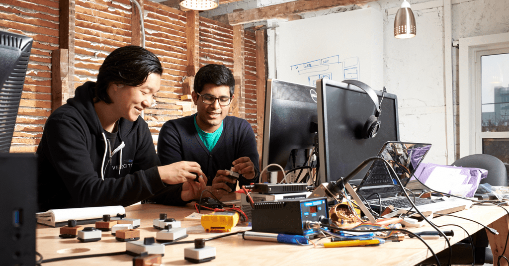 Two male students working with computer monitor wires