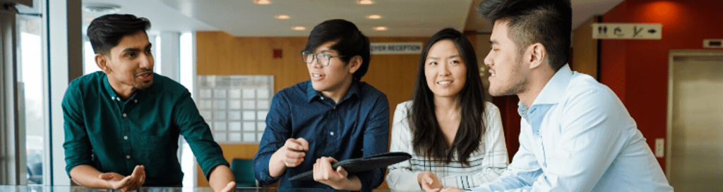 Four people standing around a high-top table chatting.