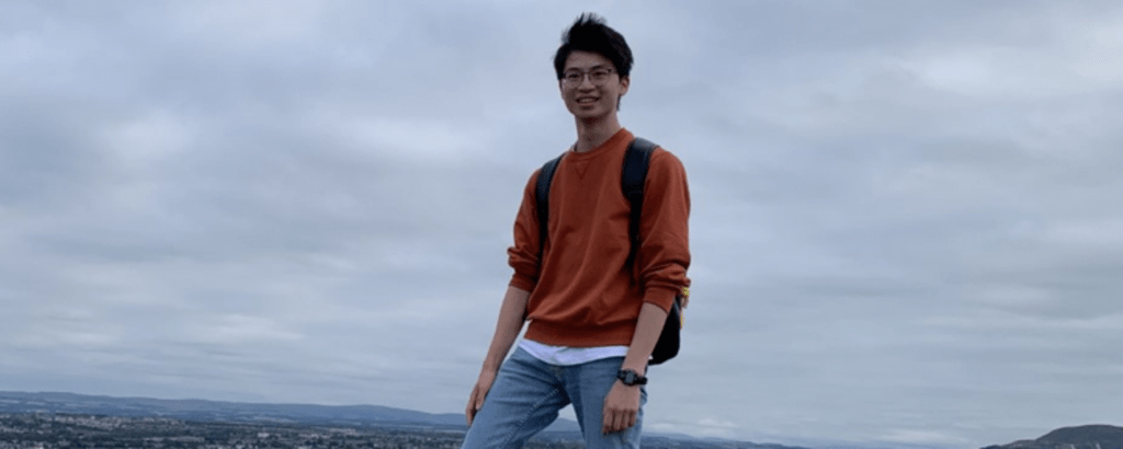 Alex standing at the top of a mountain 