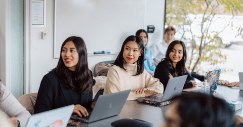 three students in meeting room with laptops