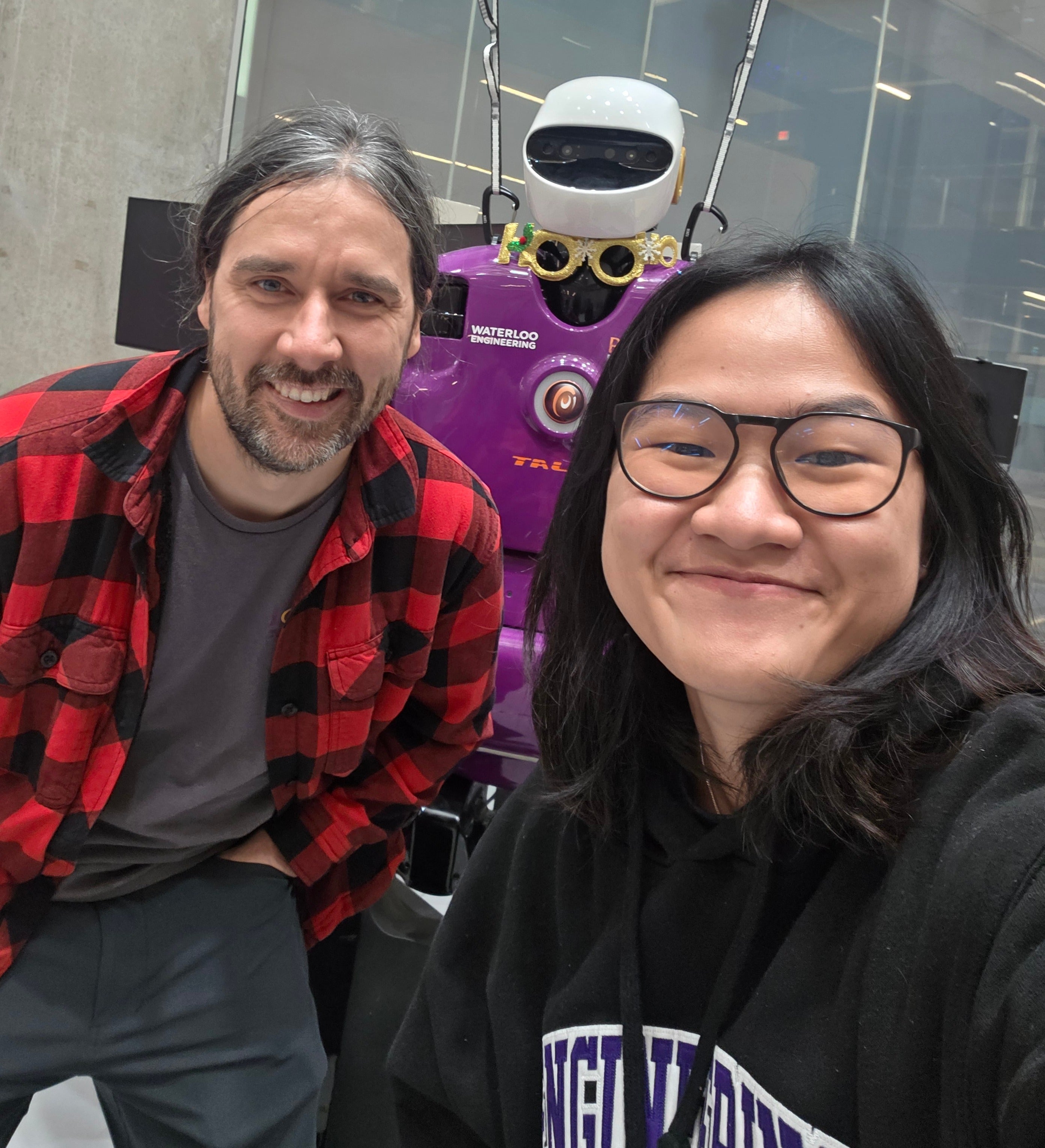 A teacher and student standing in front of a robot