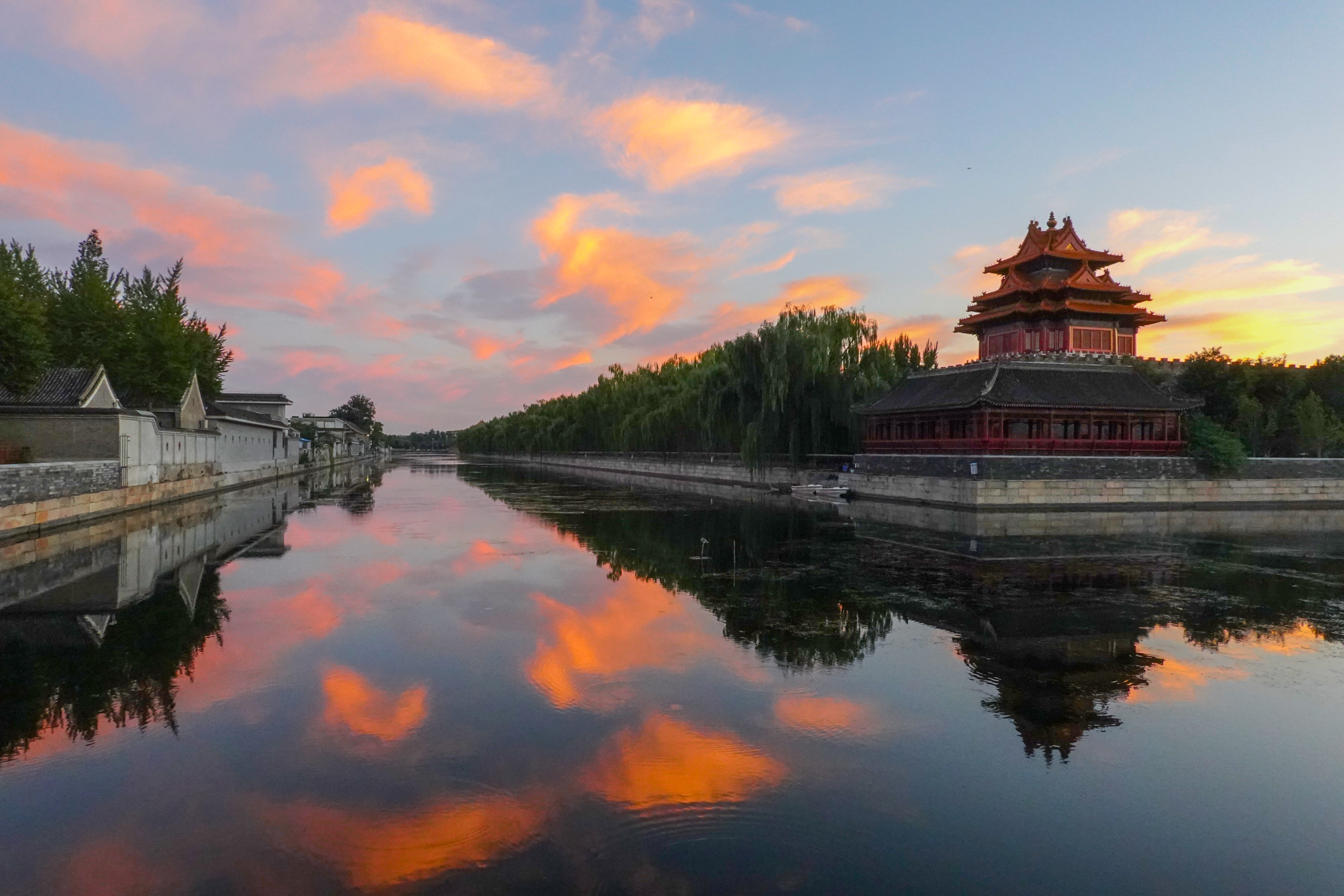Chinese traditional building riverscape with pink clouds reflecting on the still water surface. 