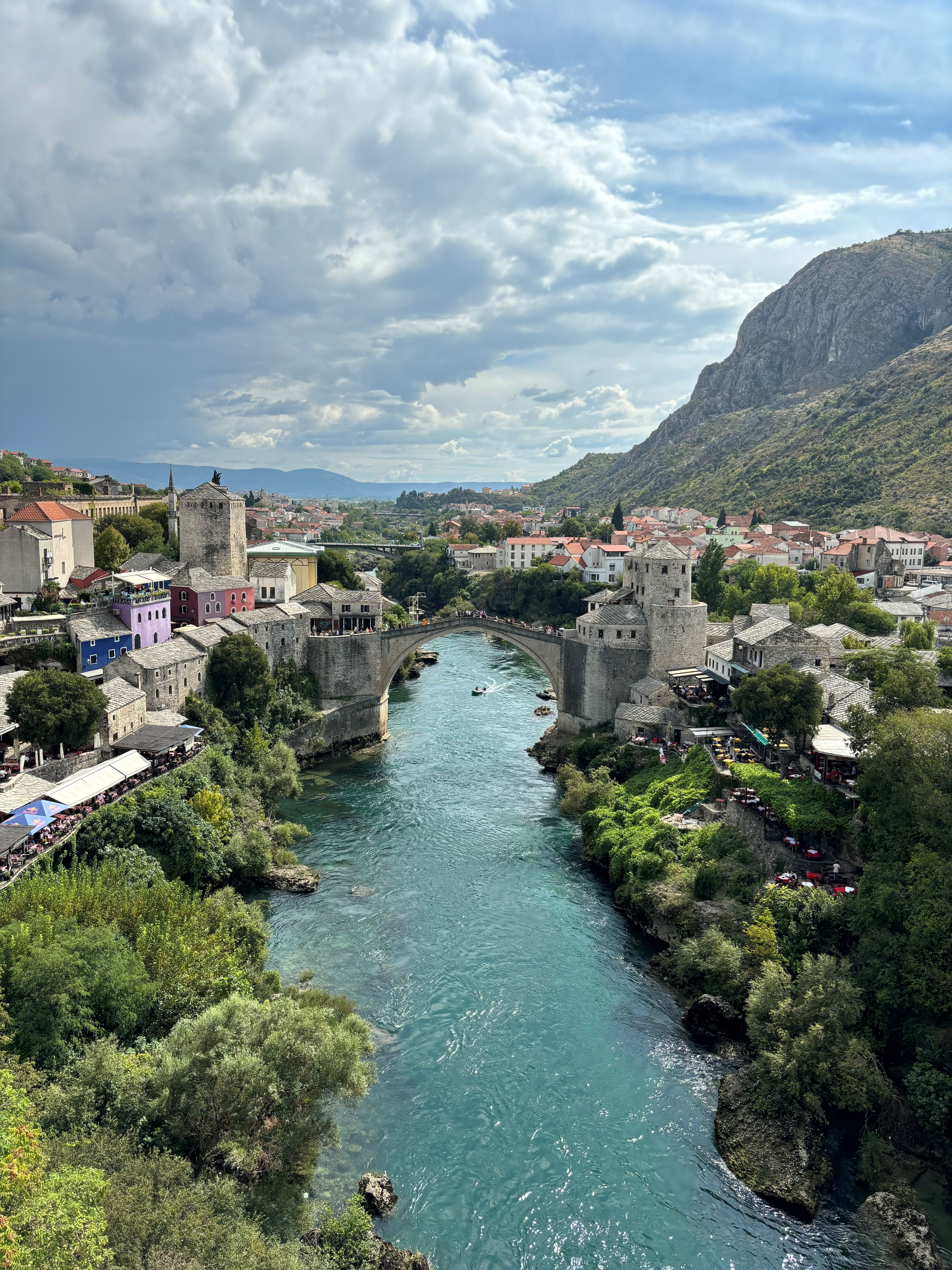 Two cities split with a turquoise river and a bridge across them,