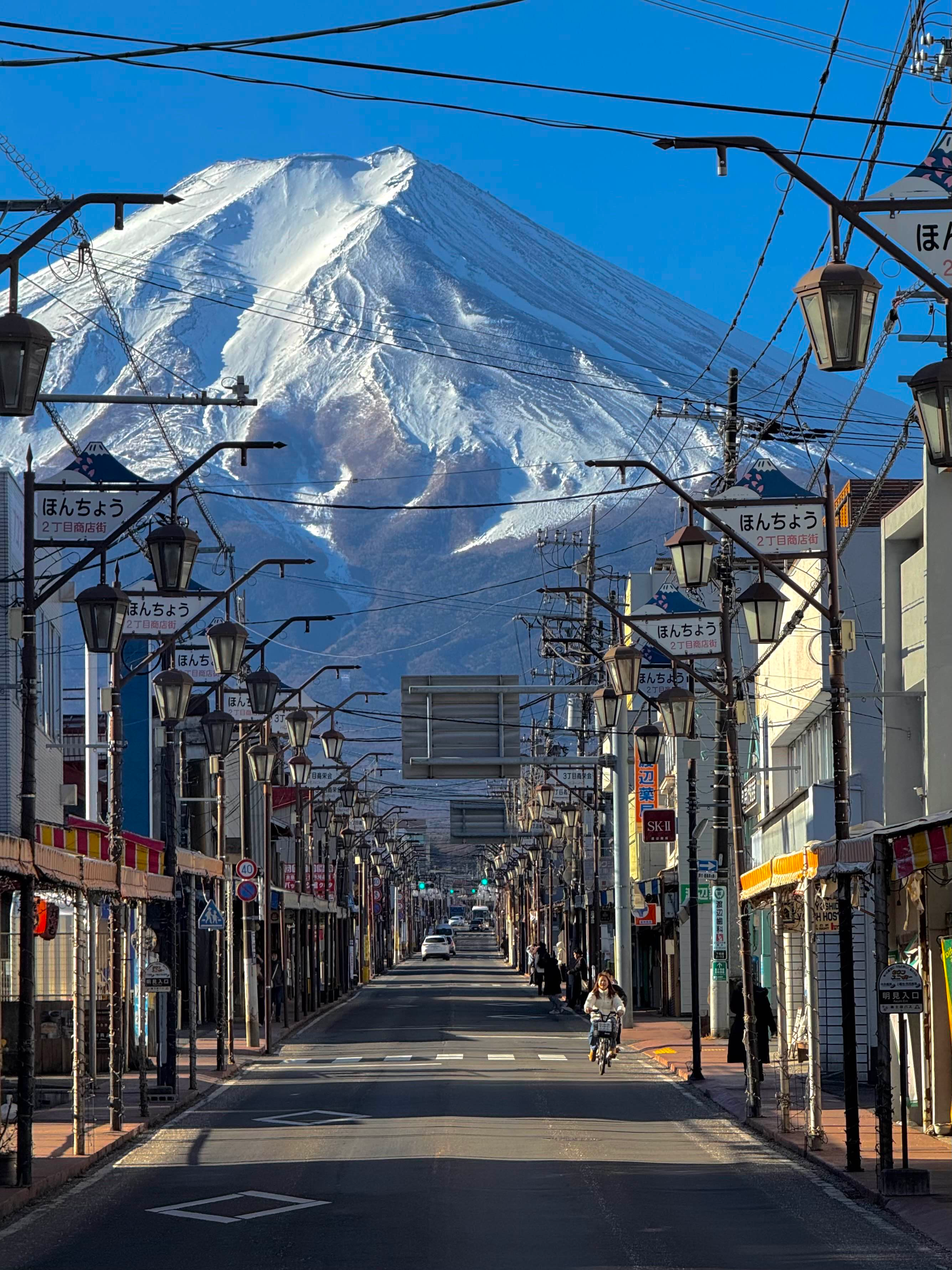Empty small-town street in Japan stretching to a large snowy mountain in the distance. 