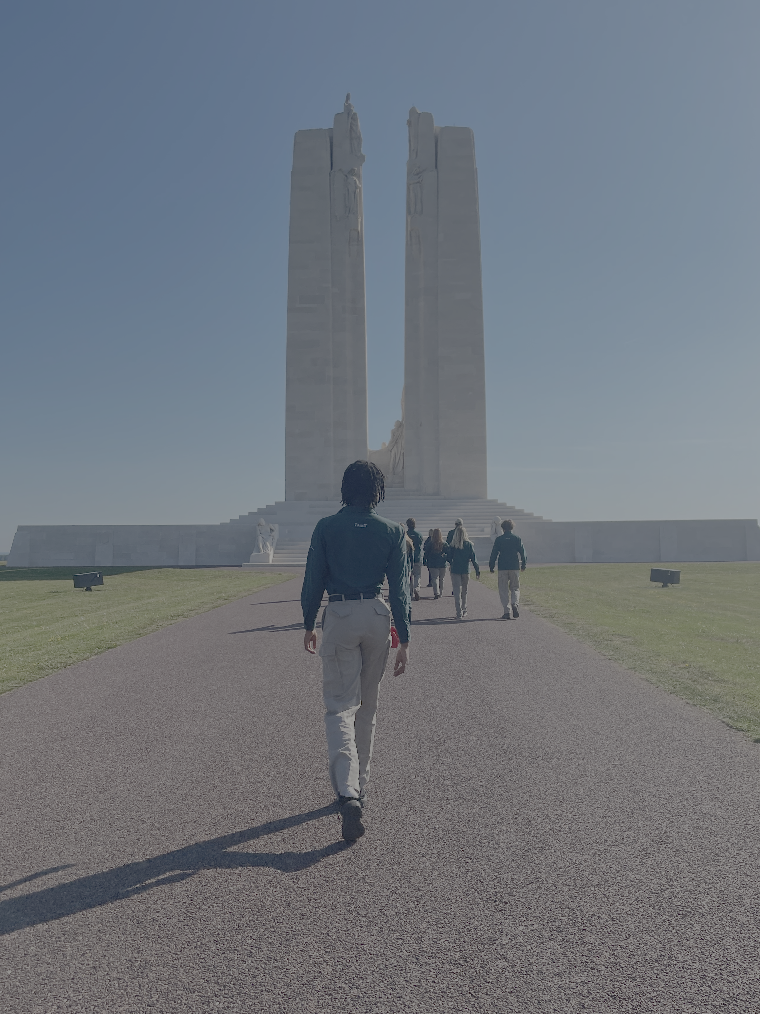 Student walking towards Vimy Ridge memorial, two large stone pillars. 