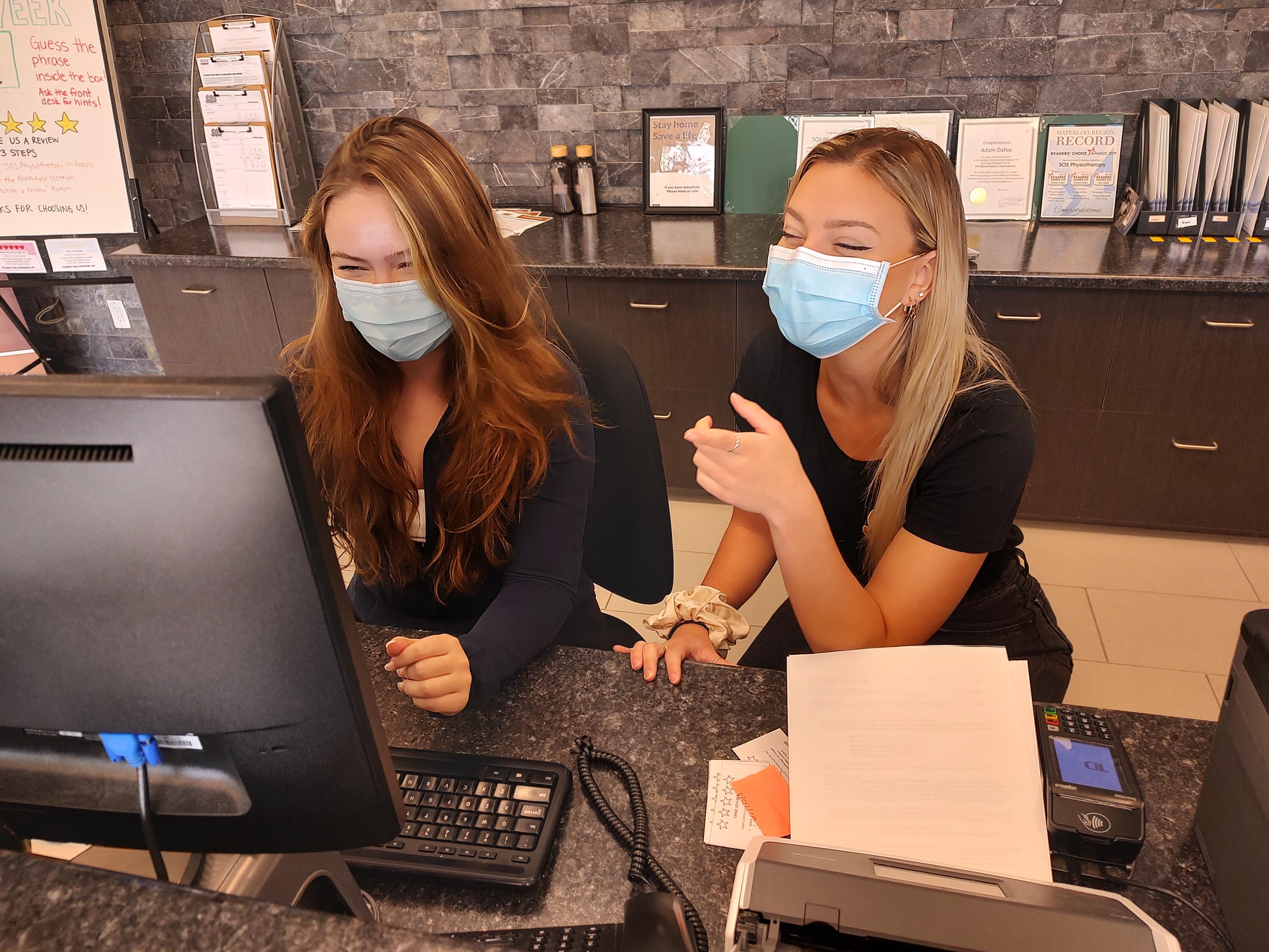 Claire Lemon with coworker at desk looking at a laptop together