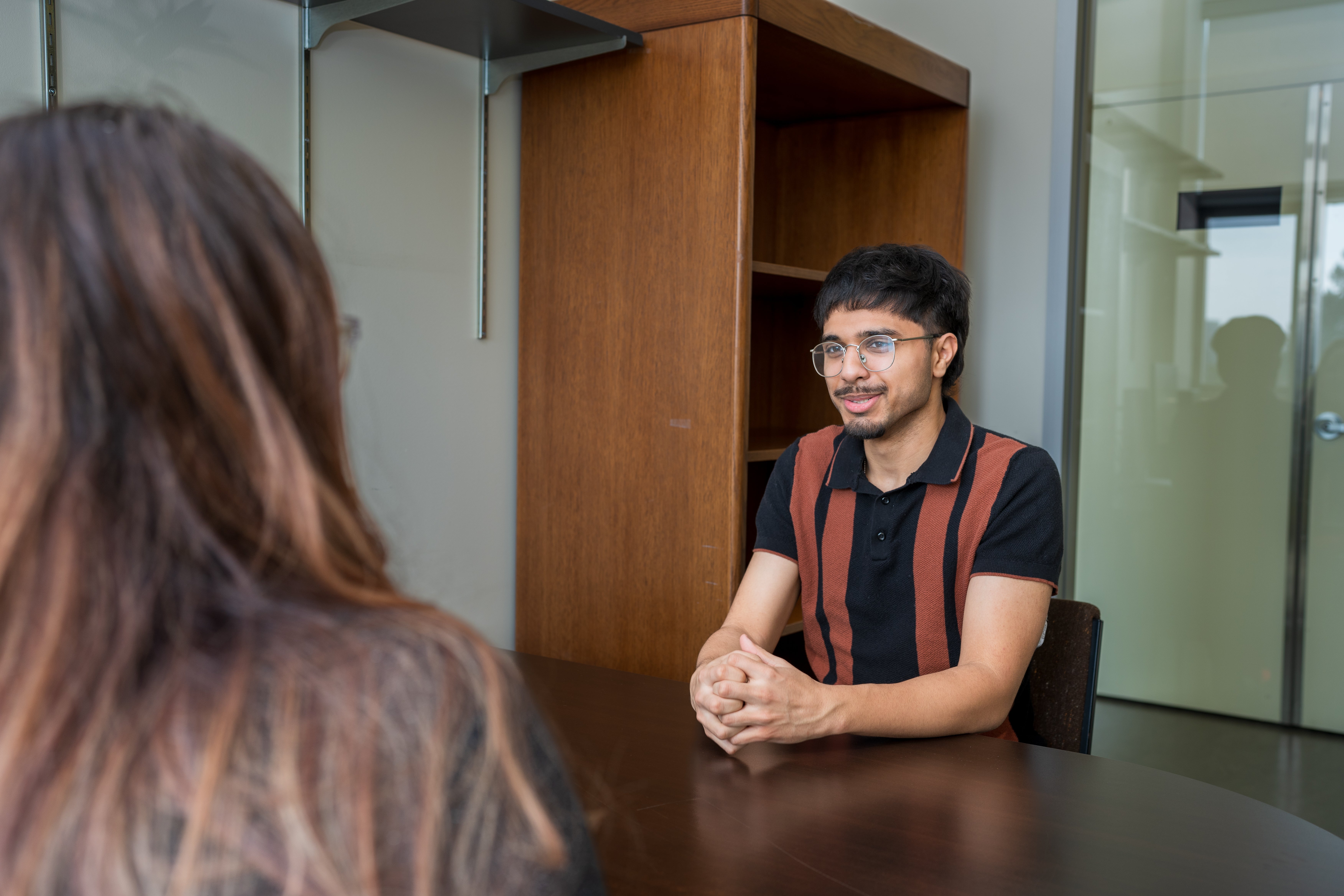 man sitting at table with hands clasped in front of him