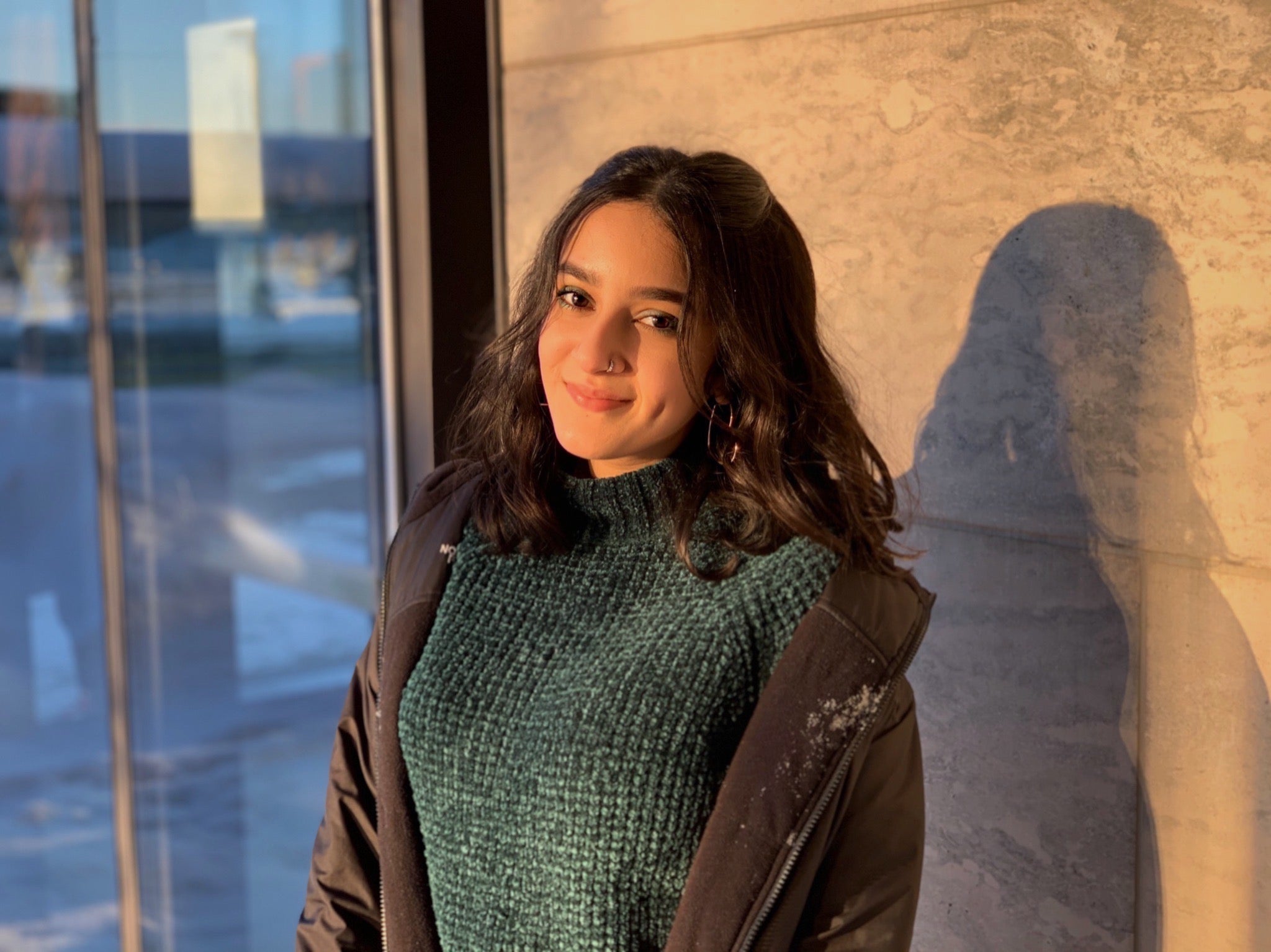 A photo of Falak smiling in front of a wall.