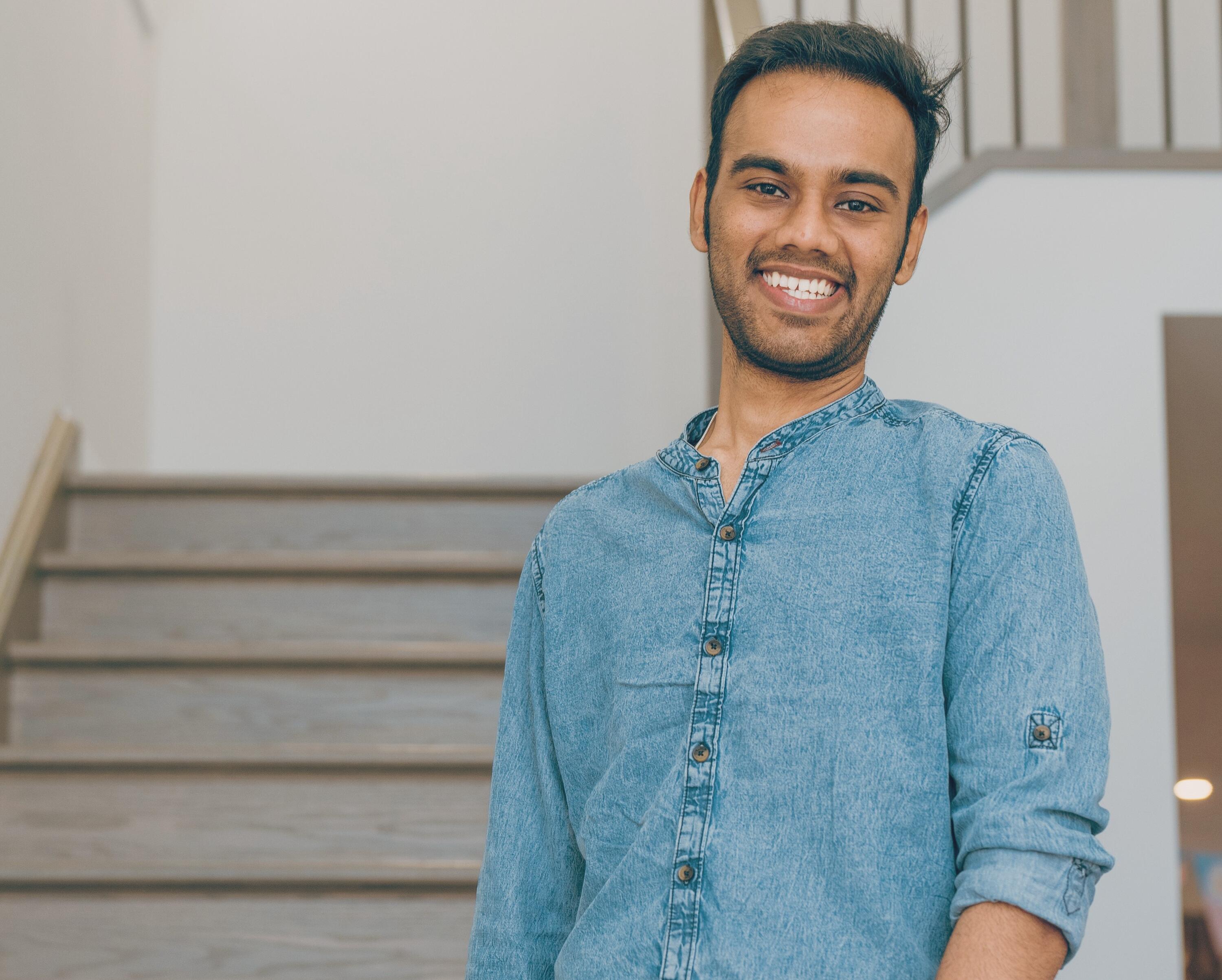 Narayanan (Nana) Ramakrishnan standing in front of a staircase smiling.