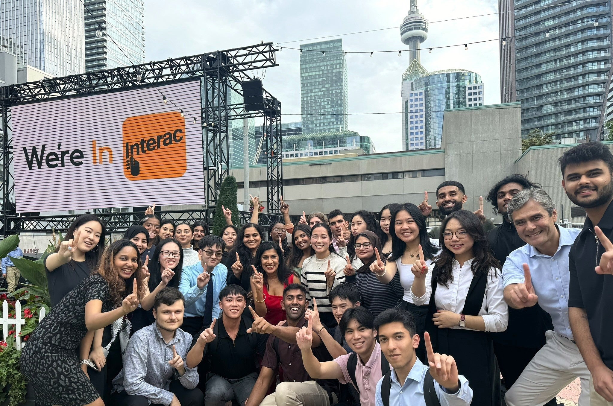 Karen Xie posing with a group of co-op students in front of Interac sign in Toronto