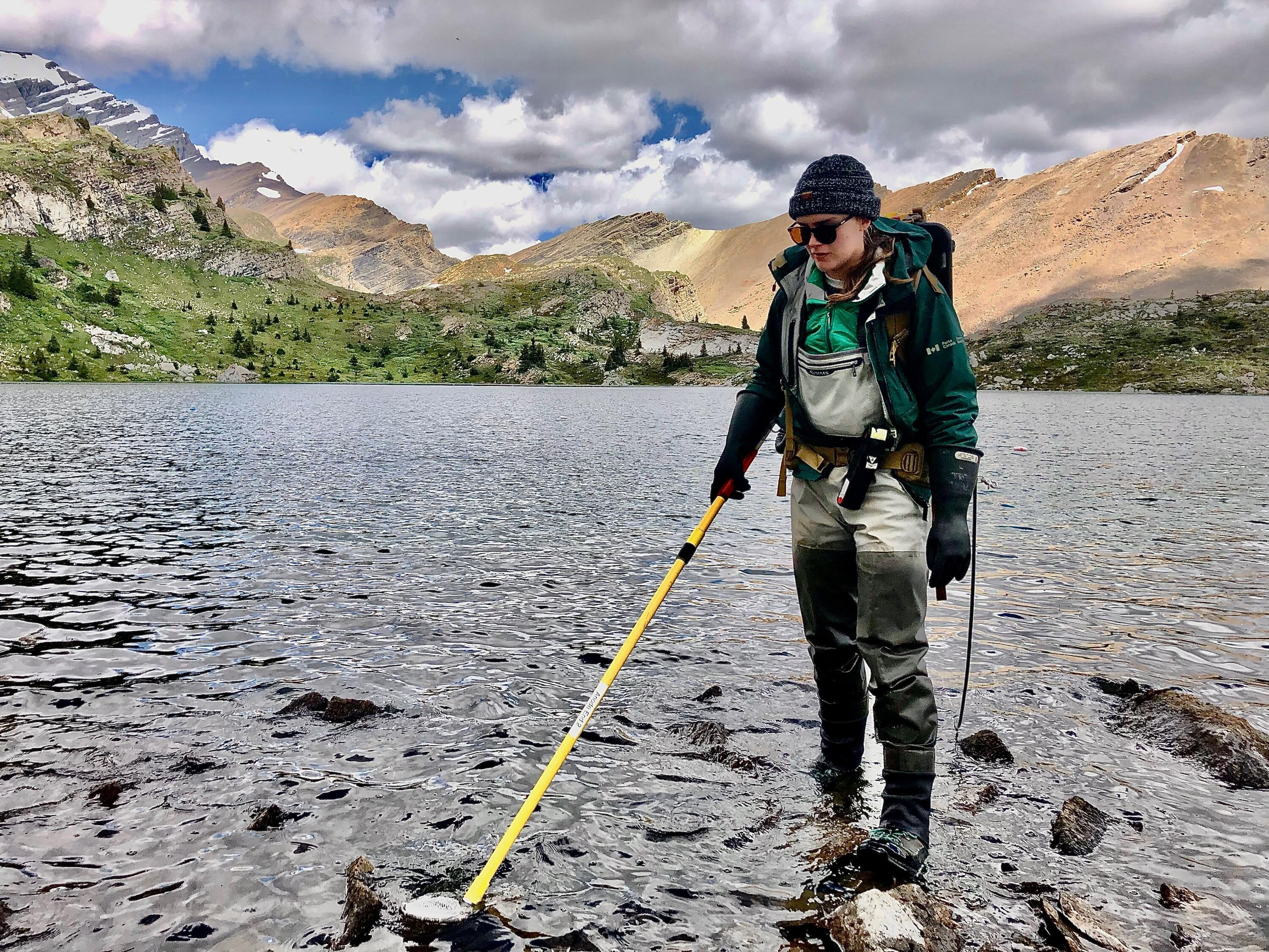 shelby standing in a lake in water overall using equipment to check the water