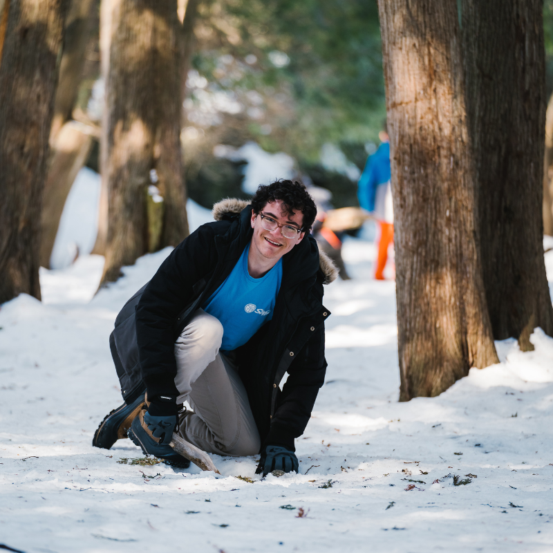 David Orlando smiling whilst digging a hole in the ground for a fire pit.