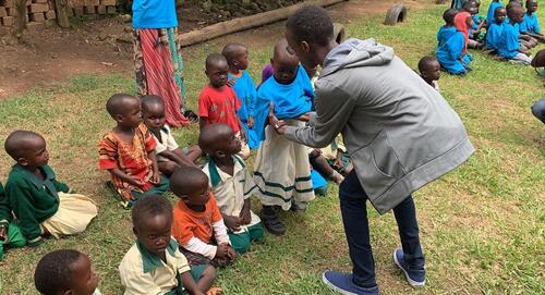 Young adult teaching children in Uganda