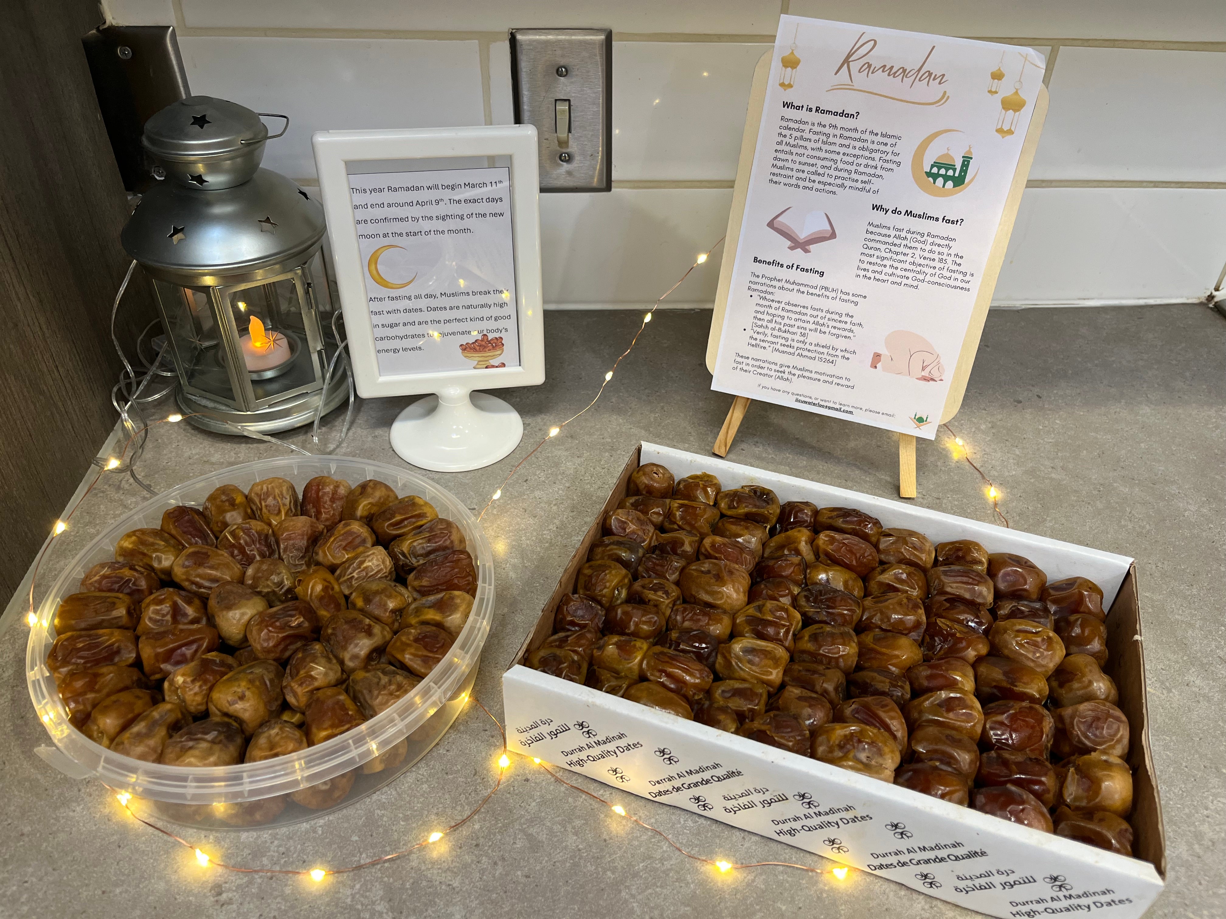 A table with some string lights, food and information on Ramadan.