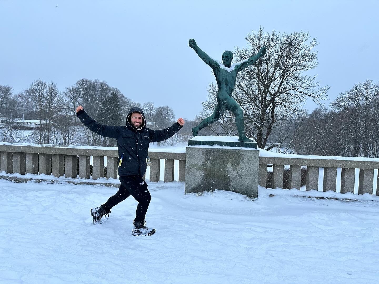 Shawn with his arms in the air, mimicking the pose of a statue behind him.