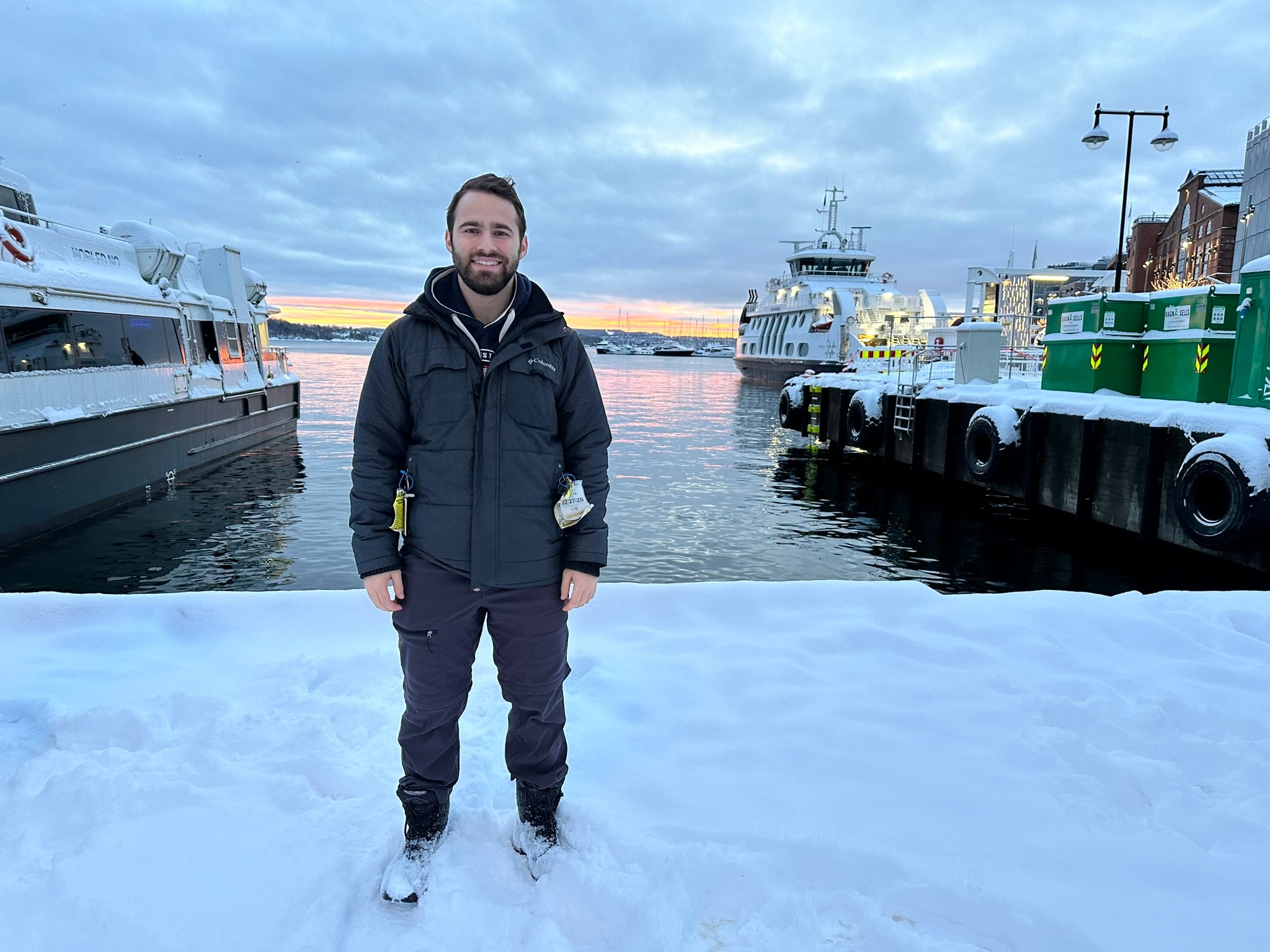 Shawn standing in front of a harbor with boats during sunset.