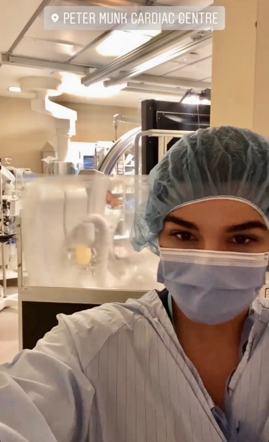 A photo of Tanveer wearing a medical mask and hair net in a medical institute setting, with the text, "Peter Munk Cardiac Centre" written at the top.