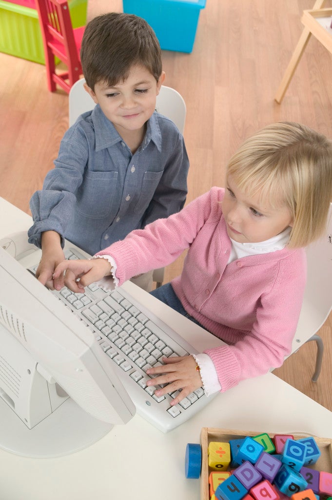 two kids playing on a computer