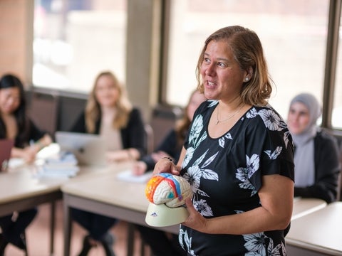 Myra teaching a class holding a model of the brain