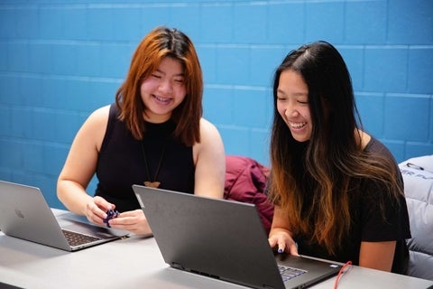 students smiling looking at a laptop