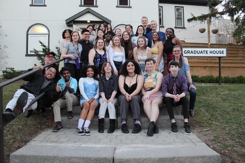 A large group of diverse students gathered on the steps of the Graduate House.