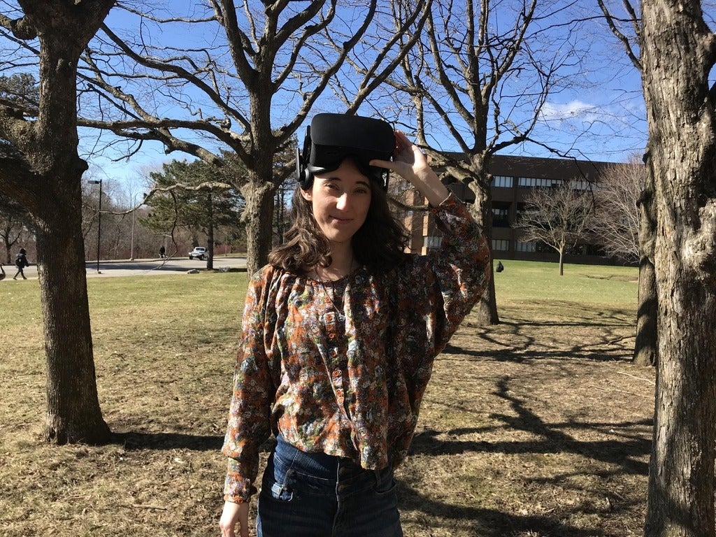Jessica Bertrand outside in a stand of trees with VR goggles