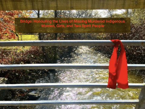 Photo on a bridge looking through railings tied with a red ribbon